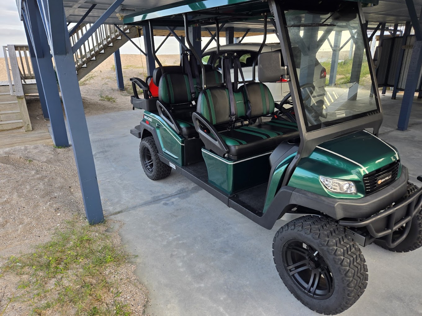 Green six-passenger golf cart parked on a Lowcountry driveway